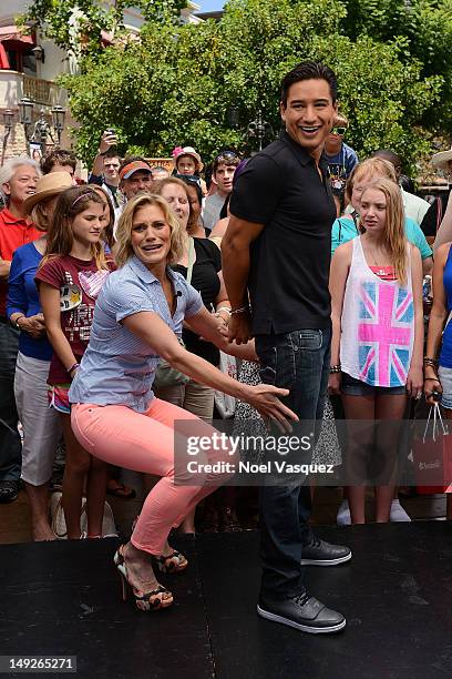 Katee Sackoff attempts to place handcuffs on Mario Lopez at "Extra" at The Grove on July 25, 2012 in Los Angeles, California.