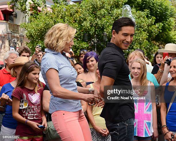 Katee Sackoff attempts to place handcuffs on Mario Lopez at "Extra" at The Grove on July 25, 2012 in Los Angeles, California.