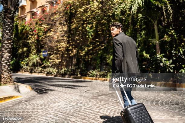 young man walking with luggage outdoors - looking around stock pictures, royalty-free photos & images