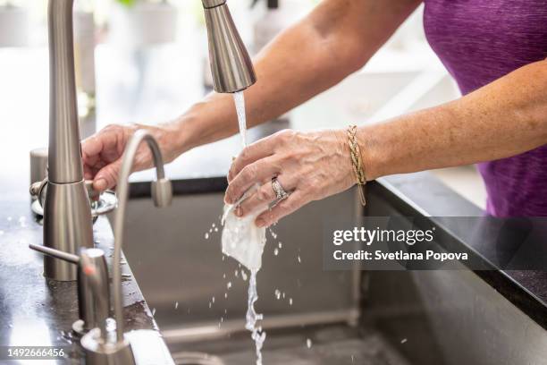 a woman is washing a sponge in a kitchen sink - cleaning sponge stock pictures, royalty-free photos & images