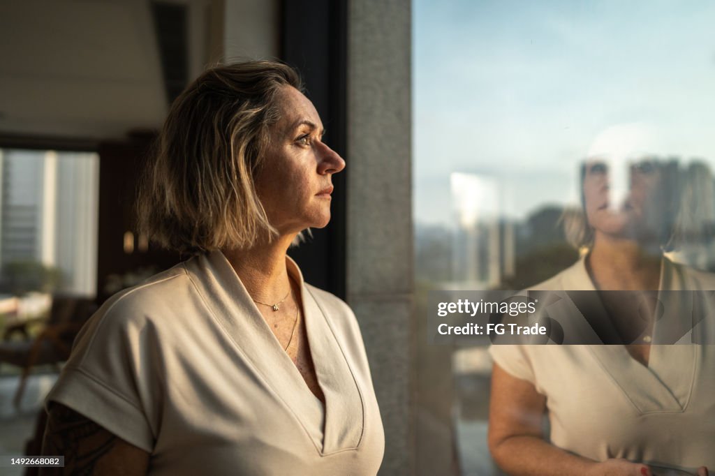 Contemplative mature woman looking through the window