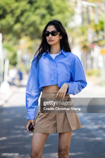 Model Sumita Bhandari wears blue cropped button shirt, brown mini skirt, sunglasses during the 76th Cannes film festival on May 23, 2023 in Cannes,...