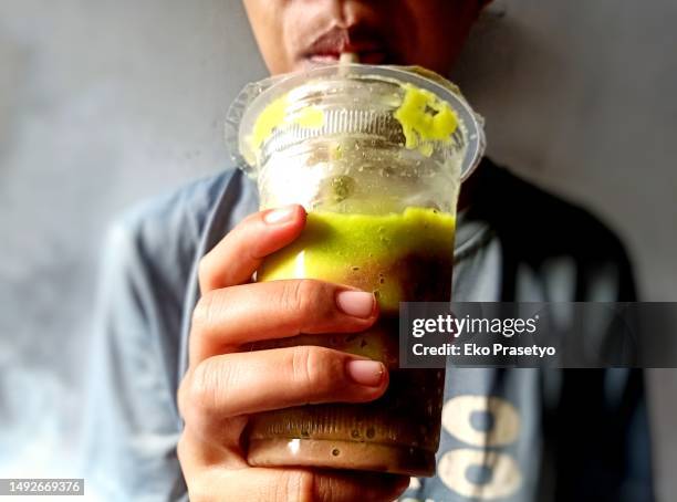 drinking avocado juice in a plastic cup - avocado smoothie stock pictures, royalty-free photos & images