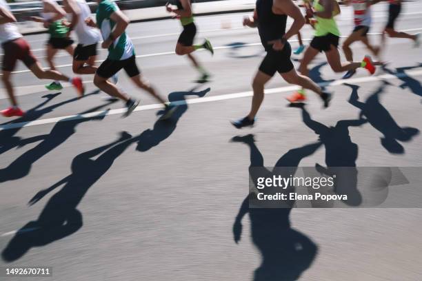 large group of people running fast in the city, defocused light and shadows sports background - marathon feet stock pictures, royalty-free photos & images