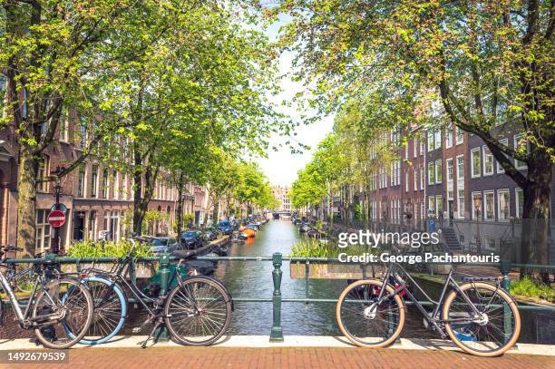 bicycles on a bridge in amsterdam, holland - amsterdam canal stockfoto's en -beelden