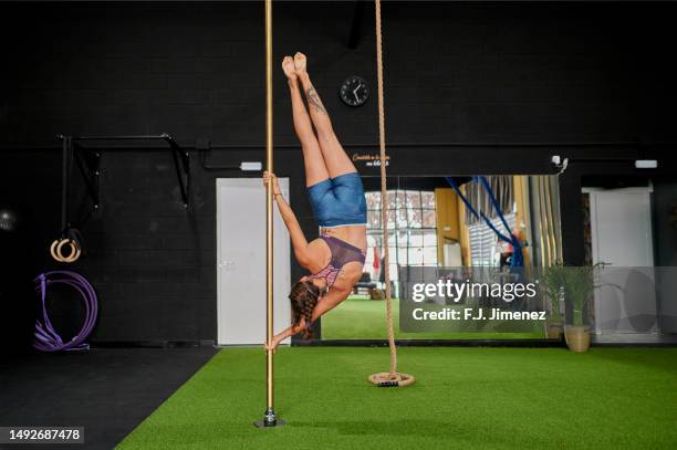 woman doing pole dance exercises in the gym - pole dance stockfoto's en -beelden