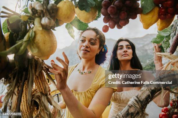 two beautiful woman shop for fruit at an outdoor italian stall. the fruit frames the image, whilst the focus remains on the woman. - zitronenbaum stock-fotos und bilder