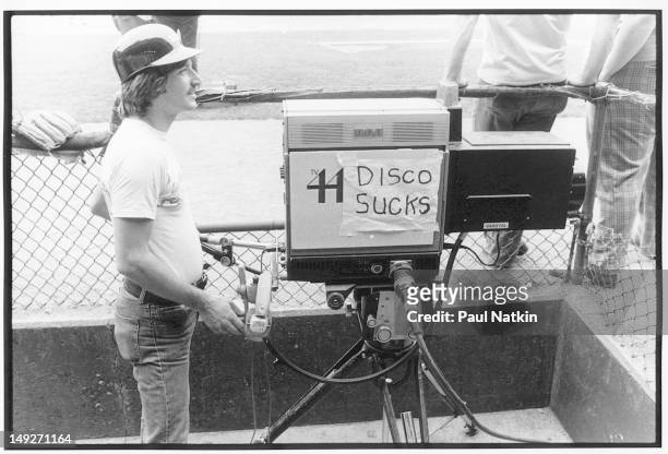 Camera for Chicago-area television station 44 carries a sign that reads 'Disco Sucks' during an anti-disco promotion at Comiskey Park, Chicago,...