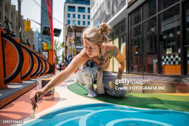 young caucasian woman artist painting sidewalk mural - artist bildbanksfoton och bilder