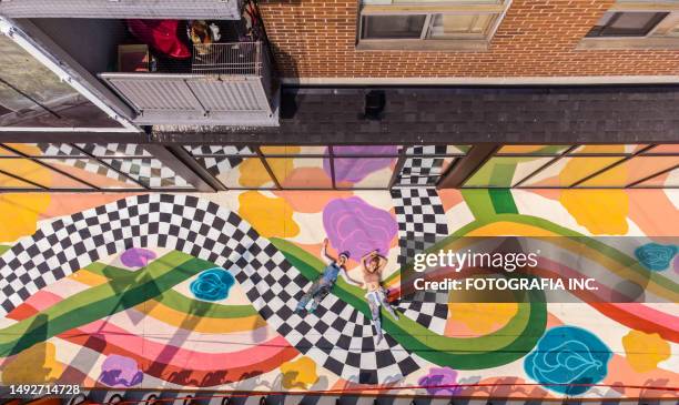 two female artists taking a break from painting large sidewalk mural - street art stockfoto's en -beelden