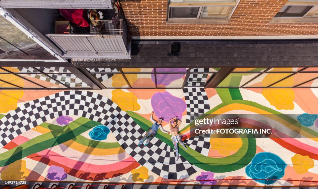 Two Female artists taking a break from painting large sidewalk mural