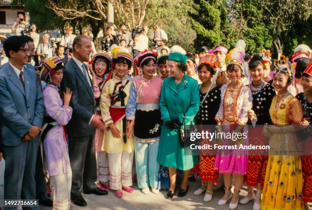 Prince Philip (1921 - 2021 and British monarch Queen Elizabeth II stand with a group of women dressed in traditional attire during a Royal Visit,...