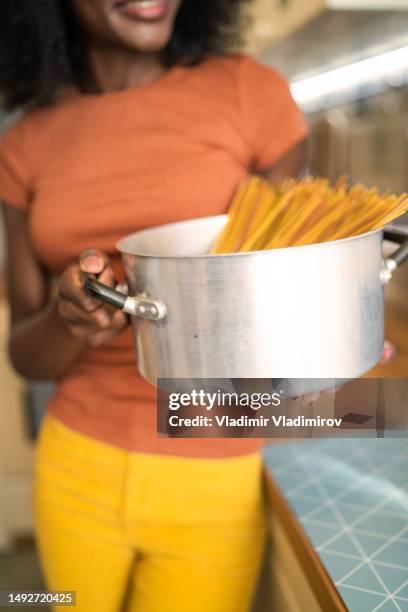 große pfanne mit ungekochten spaghetti, die von einer unbekannten frau gehalten wird - one pot pasta stock-fotos und bilder