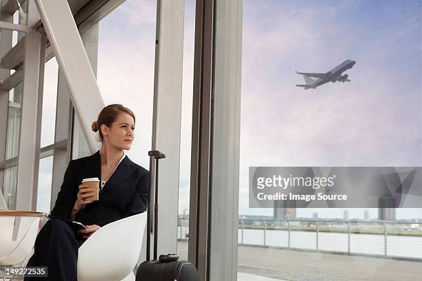 businesswoman drinking coffee in airport - businesswoman in suit jackets stock-fotos und bilder