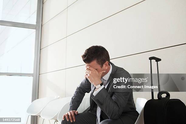 businessman waiting with luggage, head in hands - impatient stock-fotos und bilder