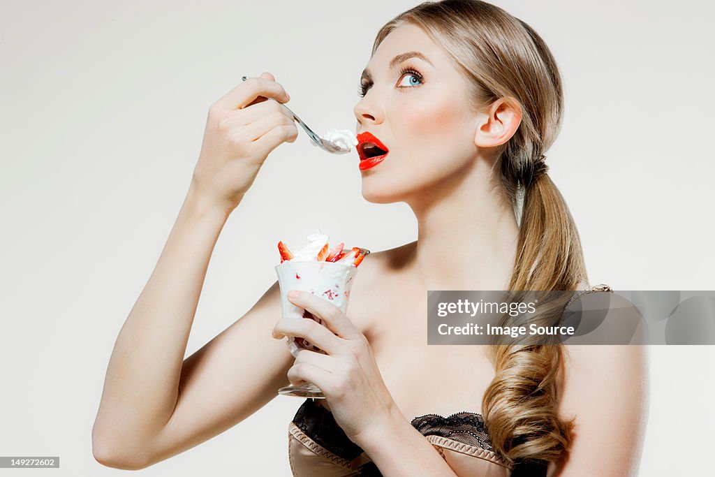 Young woman eating strawberries and cream