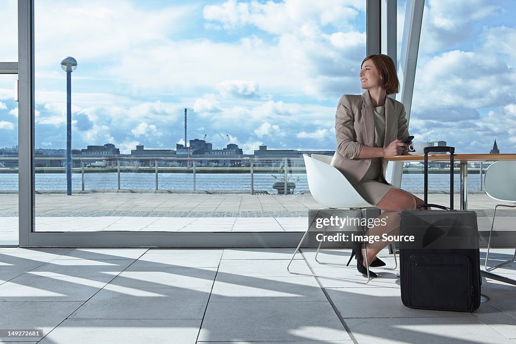 Businesswoman sitting in airport with suitcase