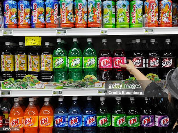Woman shops for Fraser & Neave Ltd. Soft drinks at a supermarket in Singapore, on Thursday, July 26, 2012. Kirin Holdings Co., Japan's largest brewer...