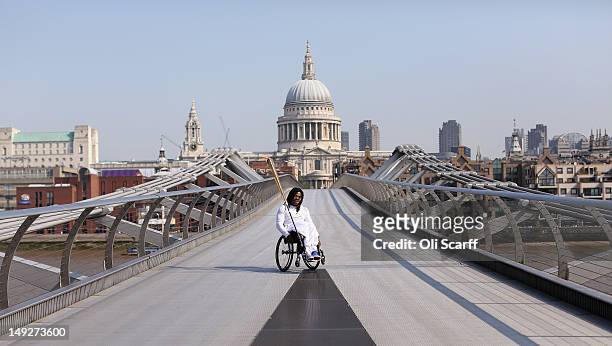 Wheelchair basketball player Adedoyin Adepitan carries the Olympic flame over Millennium Bridge in front of St Paul's Cathedral during Day 69 of the...