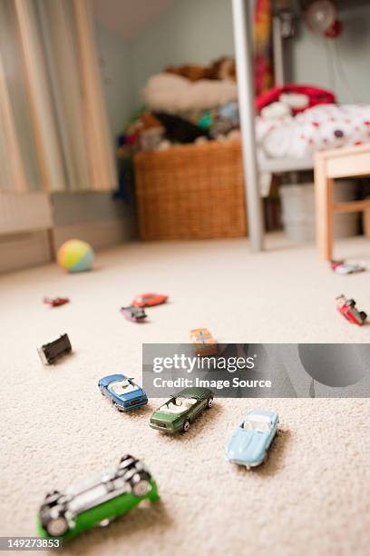 toy cars scattered across a child's bedroom - car interieur stock-fotos und bilder