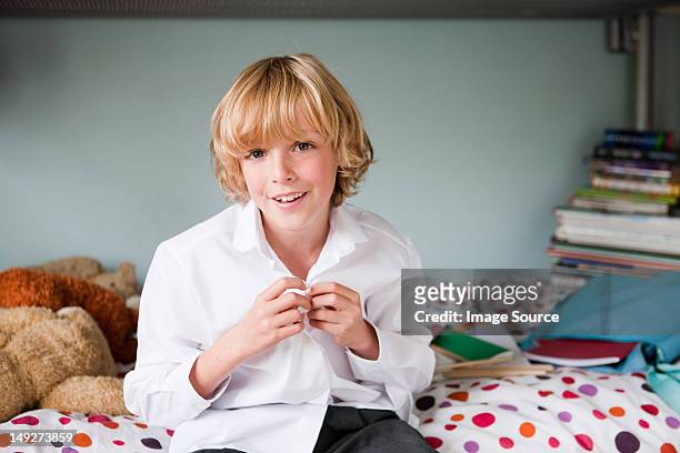 young boy buttoning up his school shirt in his bedroom - unbuttoned shirt 個照片及圖片檔