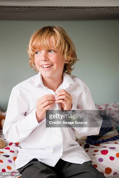 young boy haciendo los botones de su escuela camisa - abrochar fotografías e imágenes de stock