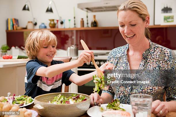 son helping to serve salad for mother at the family dinner table - respect kids stock pictures, royalty-free photos & images