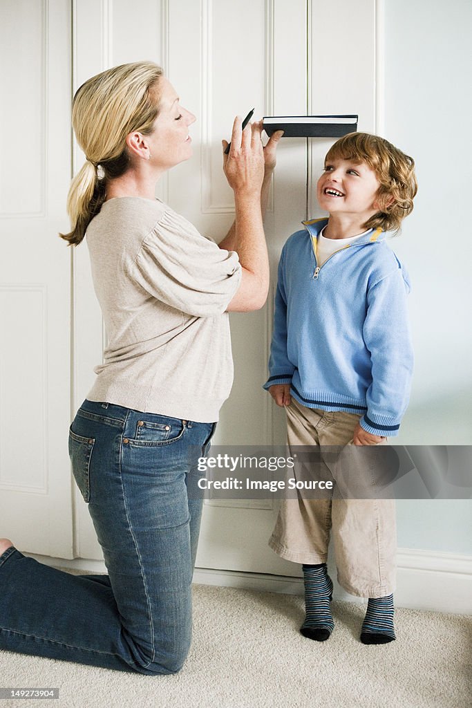 Mother measuring her son against a door with a book
