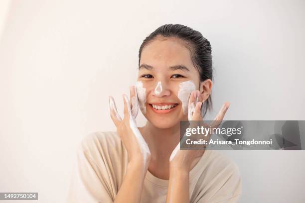 face skin care. funny asian woman cleaning facial skin with foam soap - woman washing face stockfoto's en -beelden