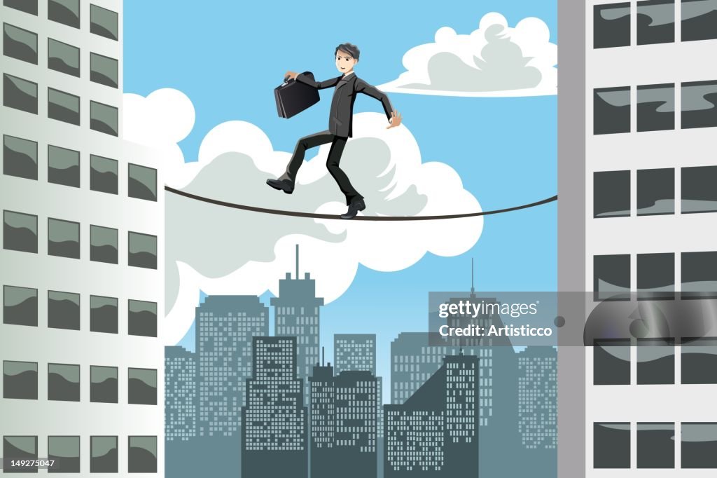 A businessman walking on a tightrope between buildings