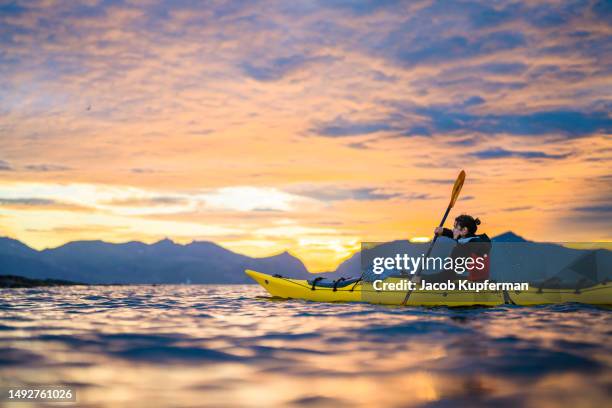 kayaking under the midnight sun in lofoten islands, norway - sole di mezzanotte foto e immagini stock