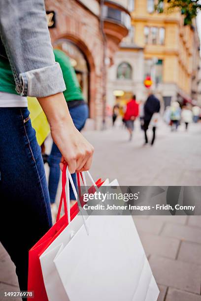 women carrying shopping bags in street - shopping bag in hand stockfoto's en -beelden