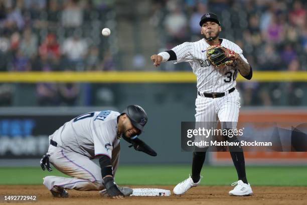 Harold Castro of the Colorado Rockies throws to first base over Yuli Gurriel of the Miami Marlins in the seventh inning at Coors Field on May 23,...