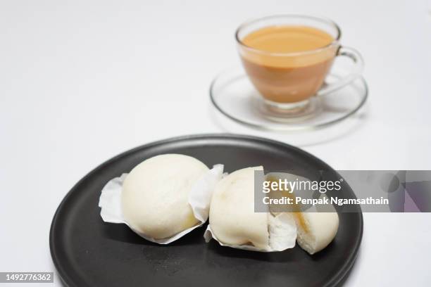 cream steamed bun in black plate and hot milk tea in clear grass coffee cup - close up bread roll black backdrop horizontal stock pictures, royalty-free photos & images