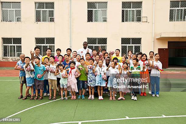 In this handout image provided by Arsenal FC, Abou Diaby and Johan Djourou pose with a group of young school children as they visit the Miaopu...