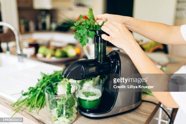woman preparing a green smoothie at home. - saftpresse stock-fotos und bilder