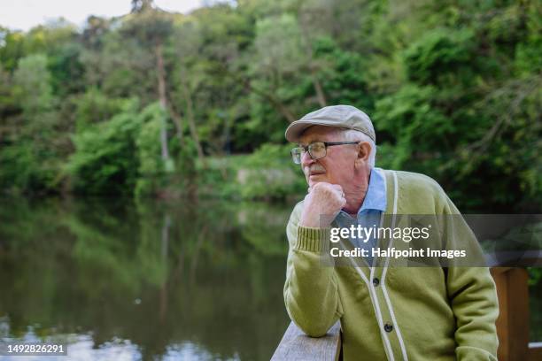 pensive senior man looking on lake. - mourner stock-fotos und bilder