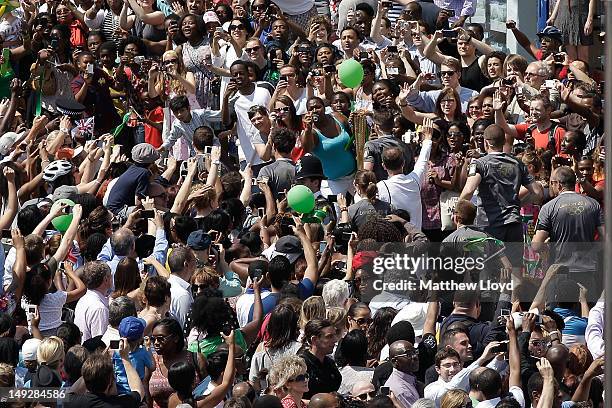 The Olympic Torch is carried through the crowd packed streets of central Brixton on July 26, 2012 in London, England. The Olympic flame is making its...