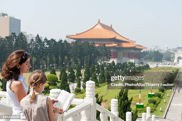 mother and daughter reading guidebook at chiang kai-shek memorial hall, taipei, taiwan - fille lire gazon photos et images de collection