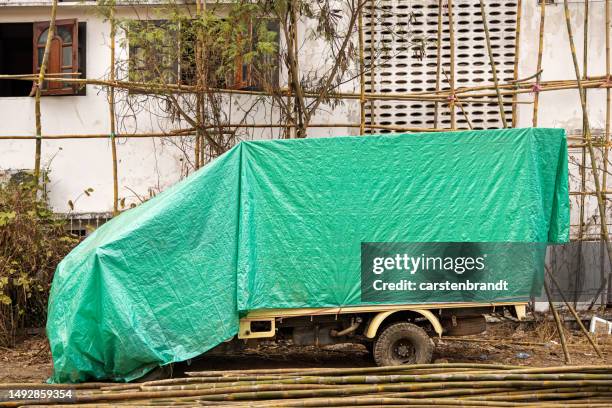 truck under a green tarpaulin at a construction site - tarpaulin stock pictures, royalty-free photos & images