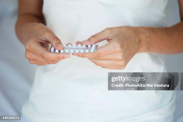 woman holding birth control pills, mid section - antibabypille stock-fotos und bilder