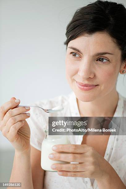 mid-adult woman eating yogurt, portrait - yogurt ストックフォトと画像