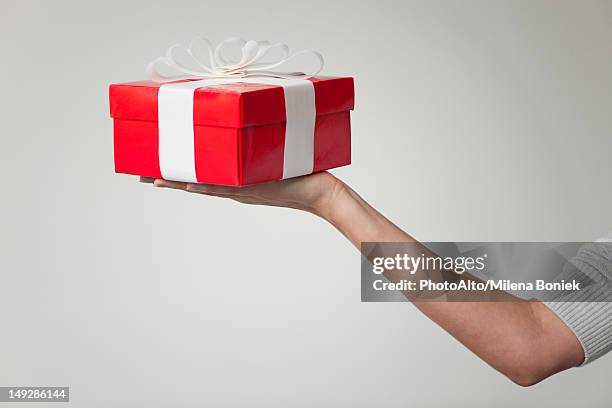 woman's arm holding out gift box, cropped - regalo di compleanno foto e immagini stock