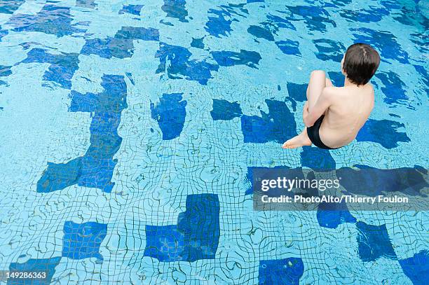 boy jumping into swimming pool, rear view - cannonball pool stock pictures, royalty-free photos & images
