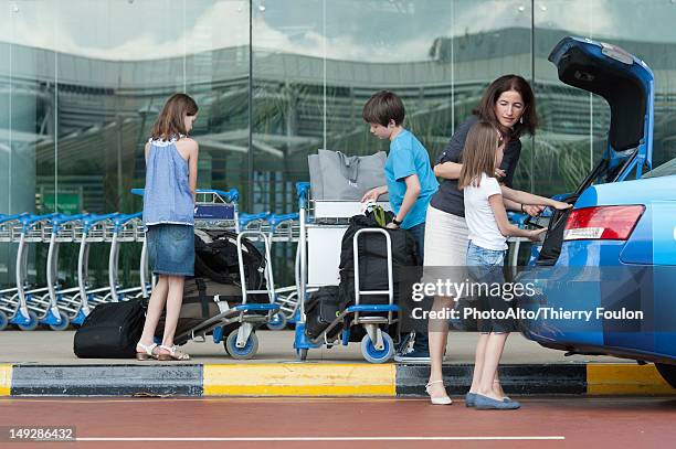 family outside of airport unloading luggage from taxi trunk - taxi boys stock pictures, royalty-free photos & images