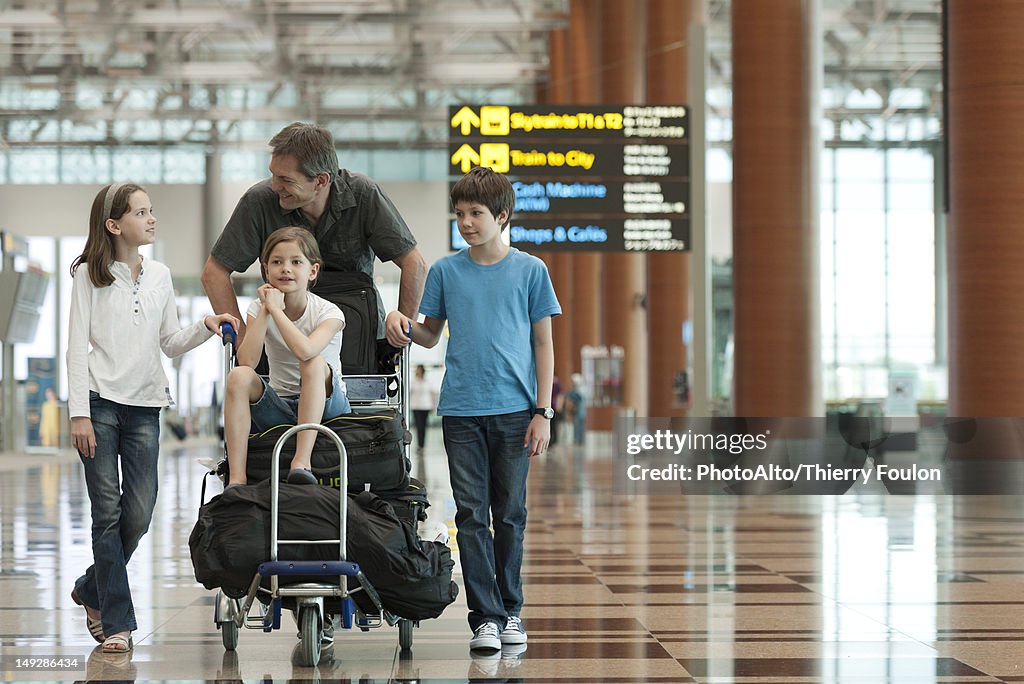 Family pushing luggage cart in airport