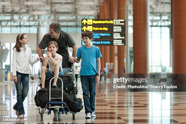 family pushing luggage cart in airport - luggage trolley stockfoto's en -beelden