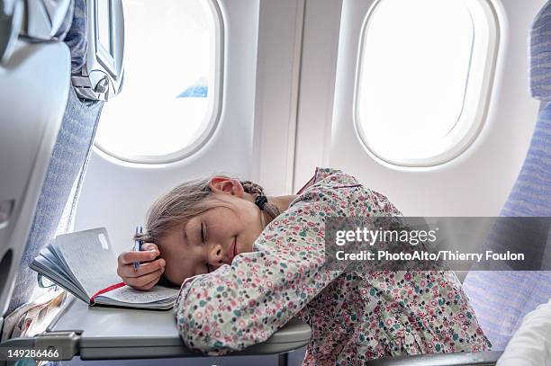 girl resting head on tray table on airplane - airplane tray stock-fotos und bilder