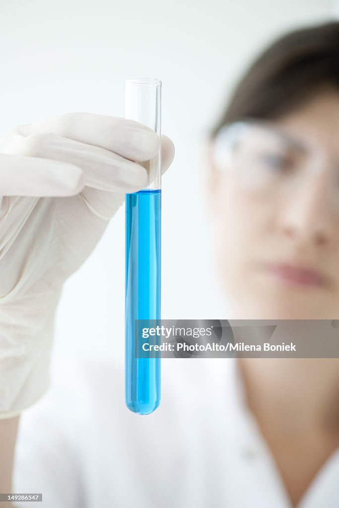 Scientist holding test tube containing blue liquid