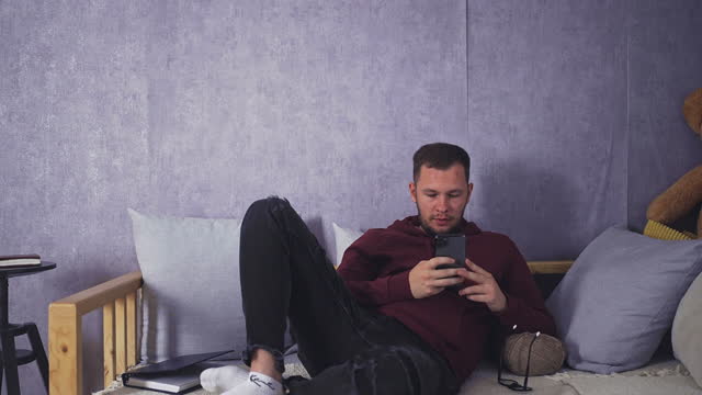 Smiling Male Enjoying Free Time With Smartphone At Home
